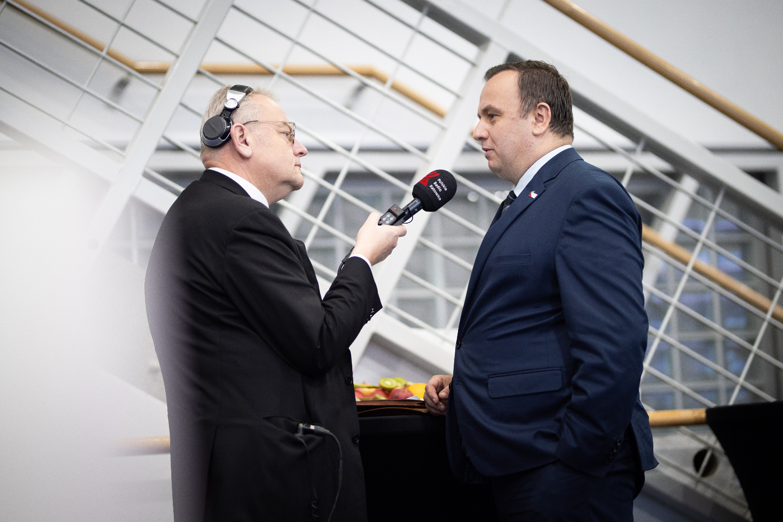 Konferencja Stadion Śląski - wywiad Marszałka Jakuba Chełstowskiego: Na fotografii Marszałek Chełstowski udziela wywiadu dziennikarzowi Polskiego Radia Katowice. Dziennikarz z słuchawkami na uszach trzyma mikrofon koloru czarnego. 