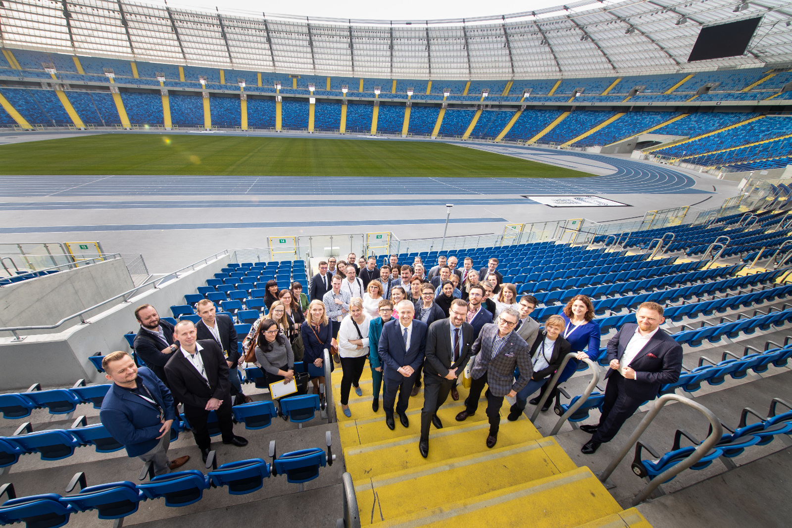 Konferencja Stadion Śląski - zdjęcie wspólne: Pamiątkowe zdjęcie grupowe uczestników konferencji w sektorze VIP z widokiem na murawę i trybuny Stadionu Śląskiego